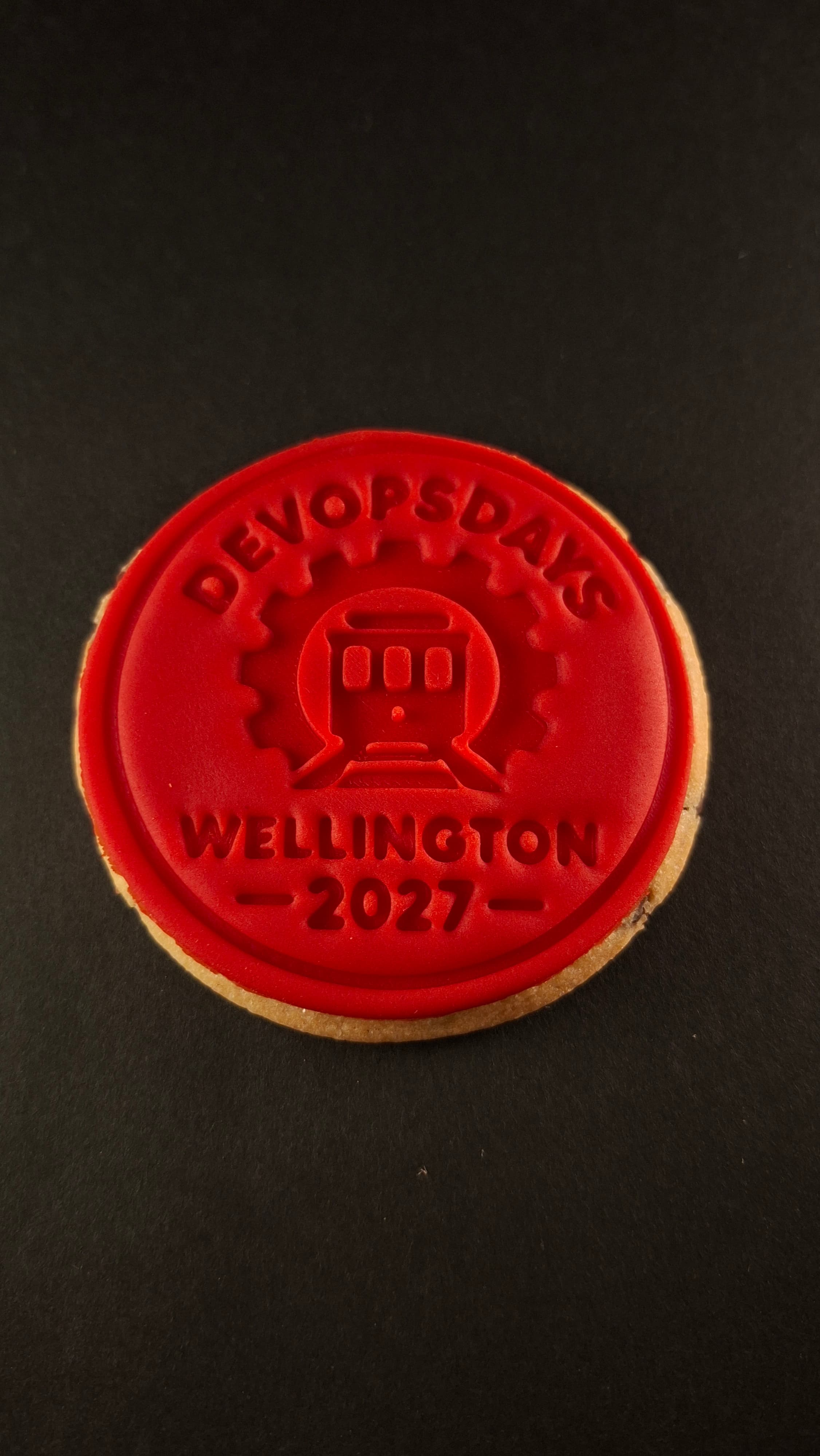 DevOpsDays Wellington branded cookie on black background