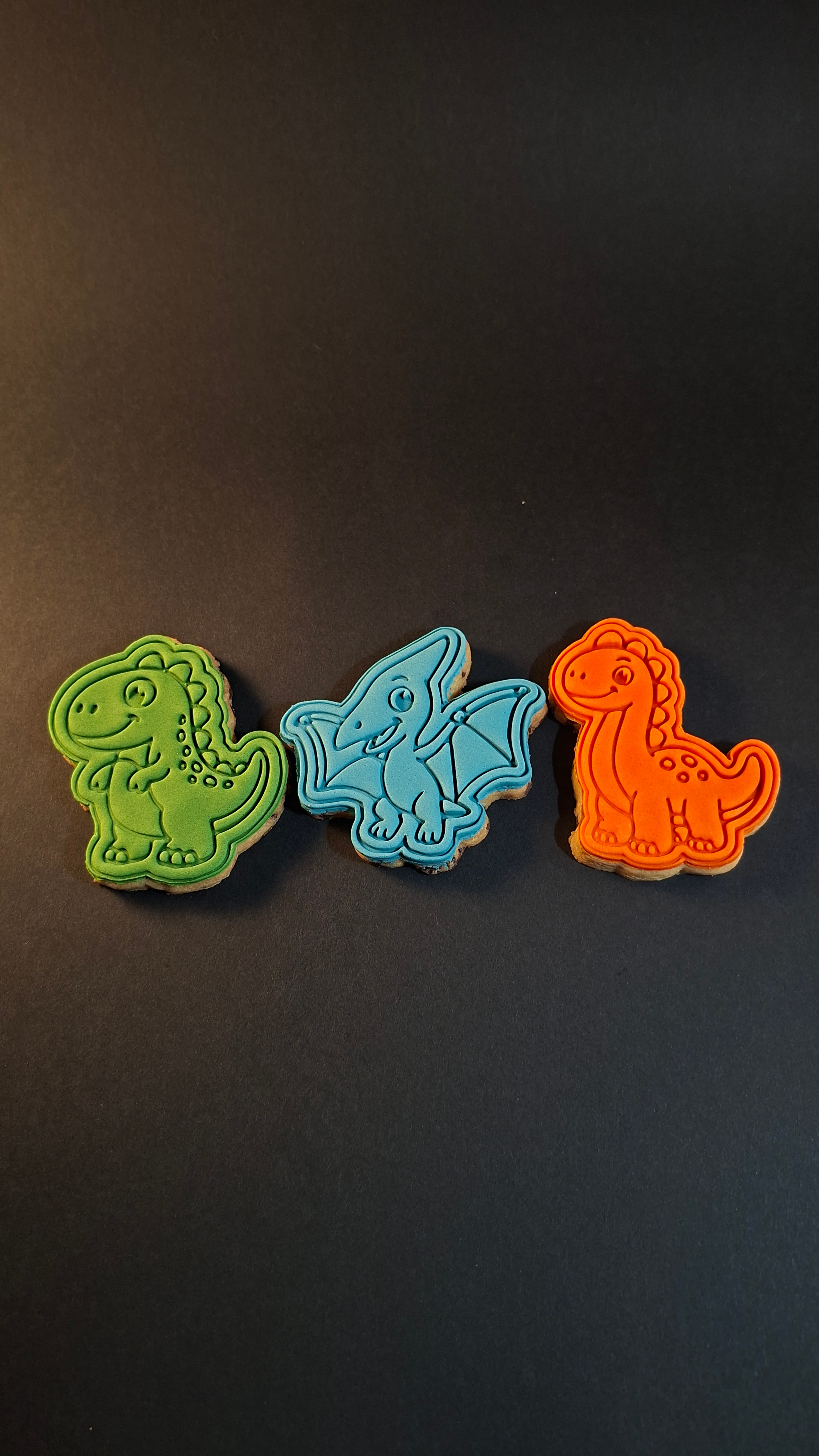 Three dinosaur cookies on black background